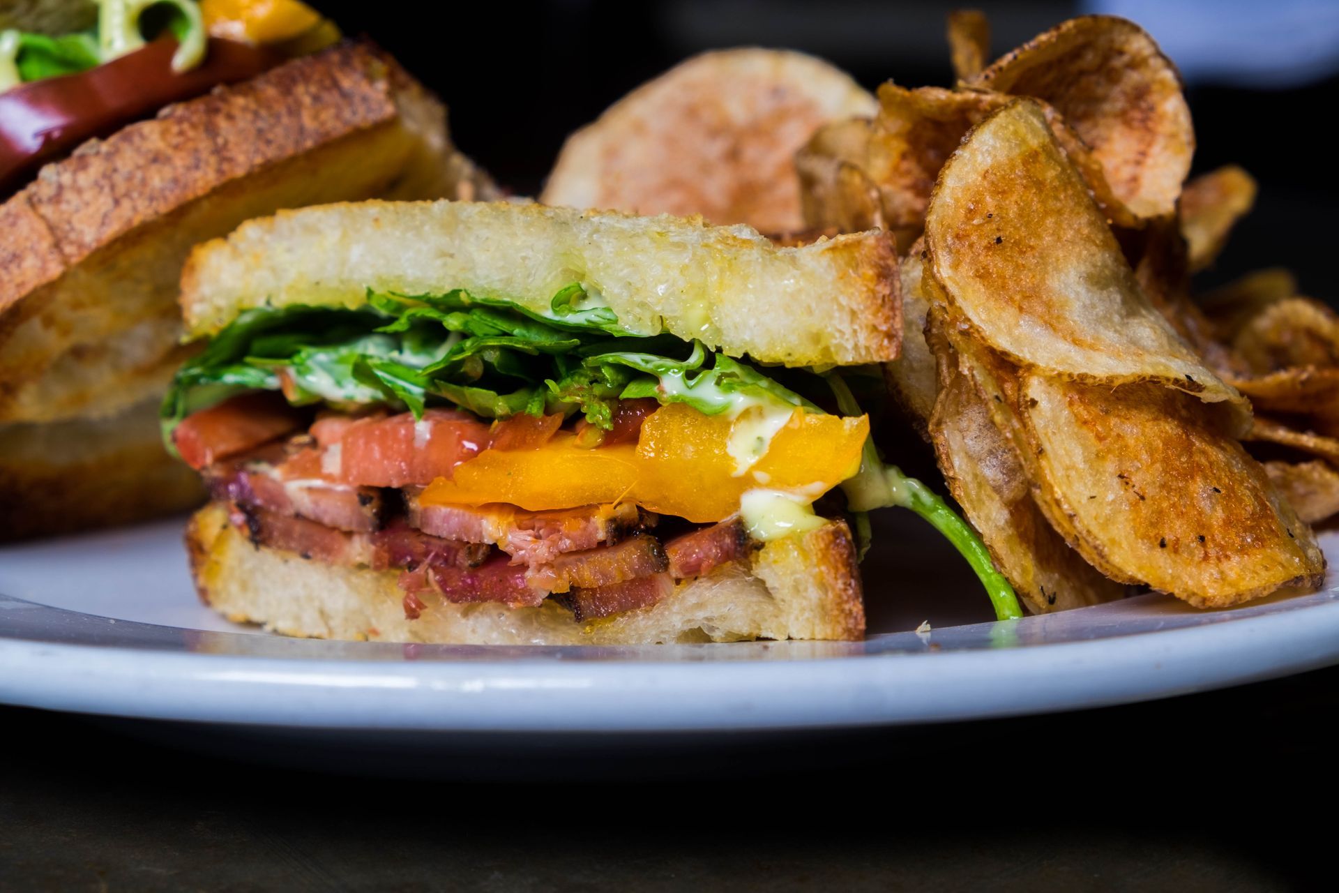 A close-up of a BLT sandwich and chips on a plate.