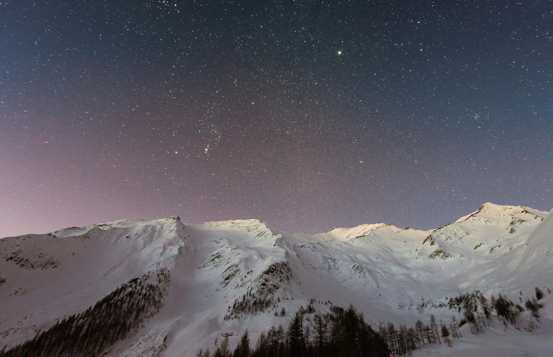 Snow-covered mountain range beneath a quiet, star-filled night sky