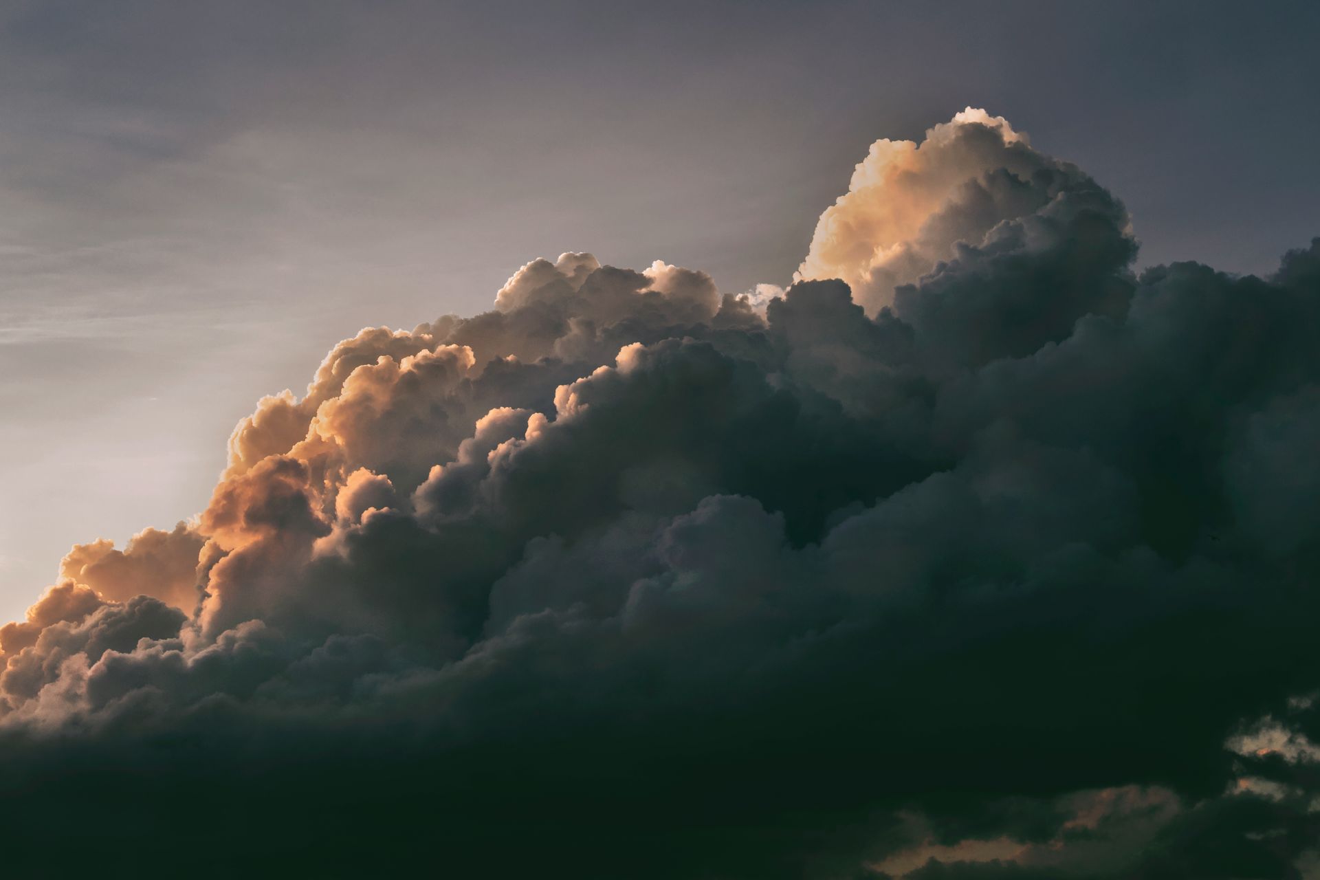 Dark storm clouds glowing with golden light at sunset.