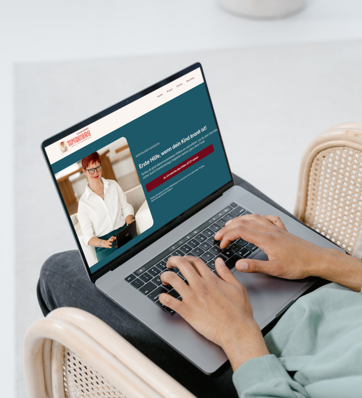 Eine Person, die in einem hellen Raum auf einem Stuhl sitzt und auf einem Laptop mit angezeigter Webseite tippt,