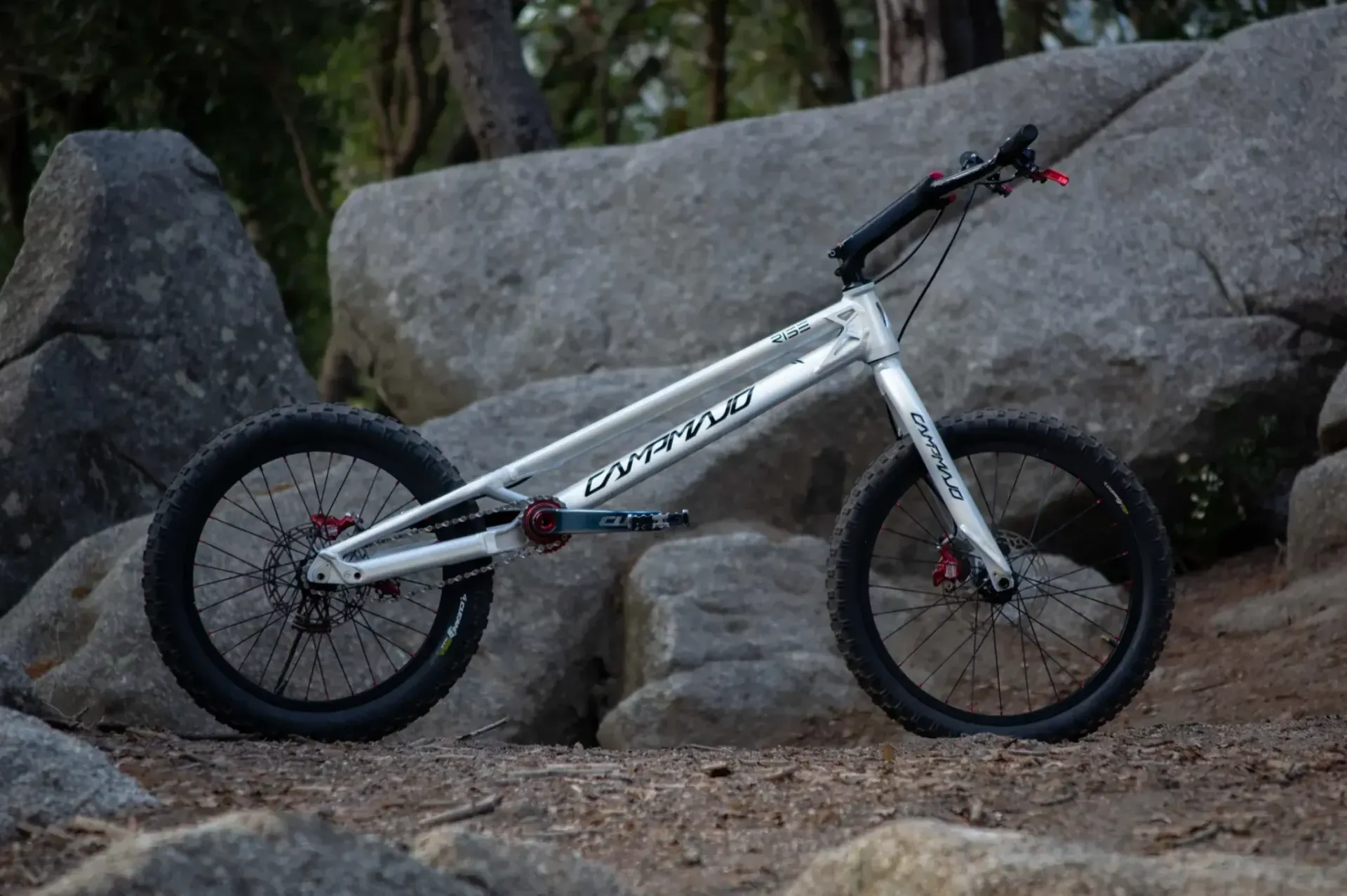 Witte BMX-fiets geparkeerd op rotsen in een bosrijk gebied