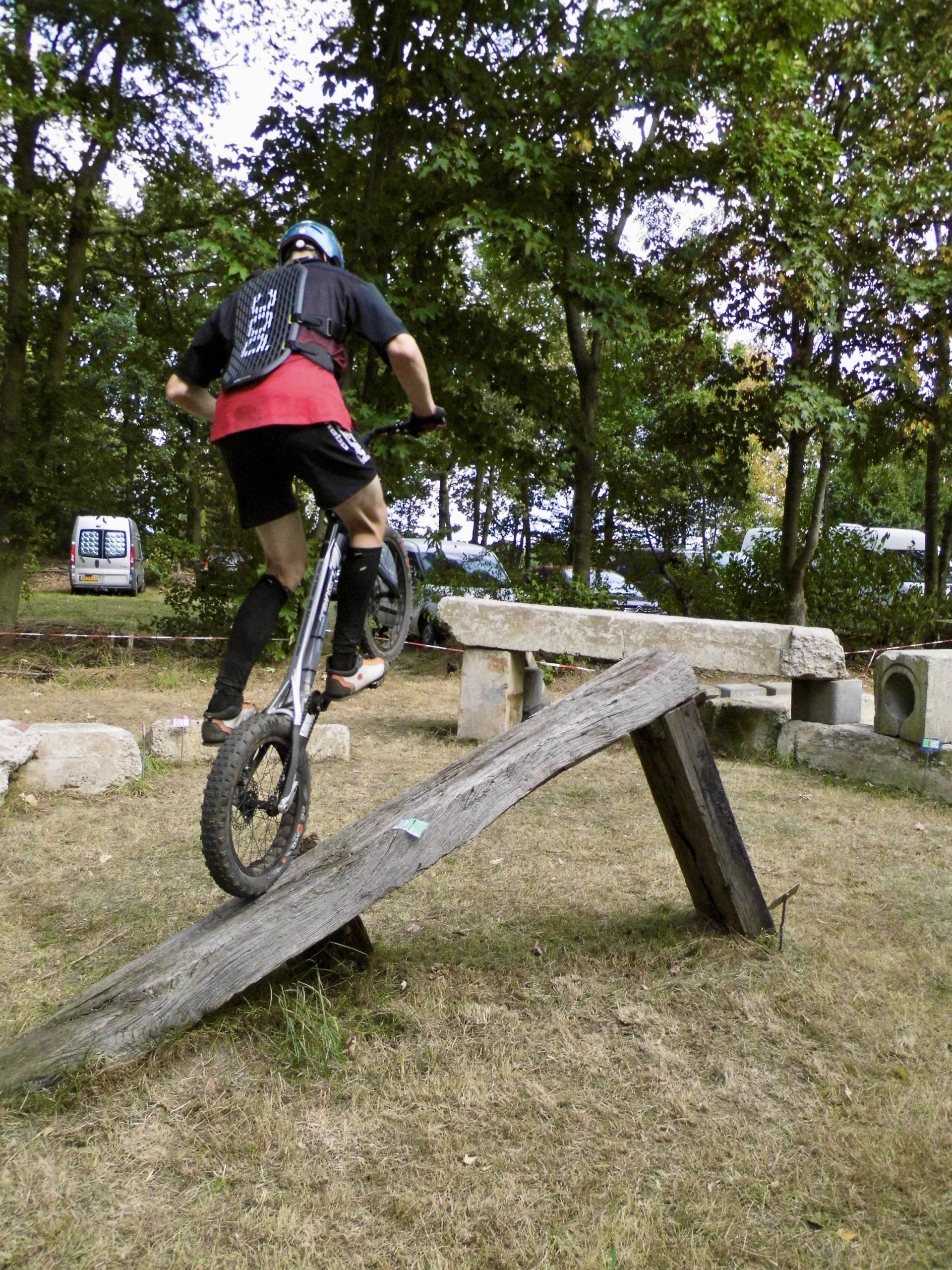 Een mountainbiker rijdt een houten helling op in een grasrijk park.