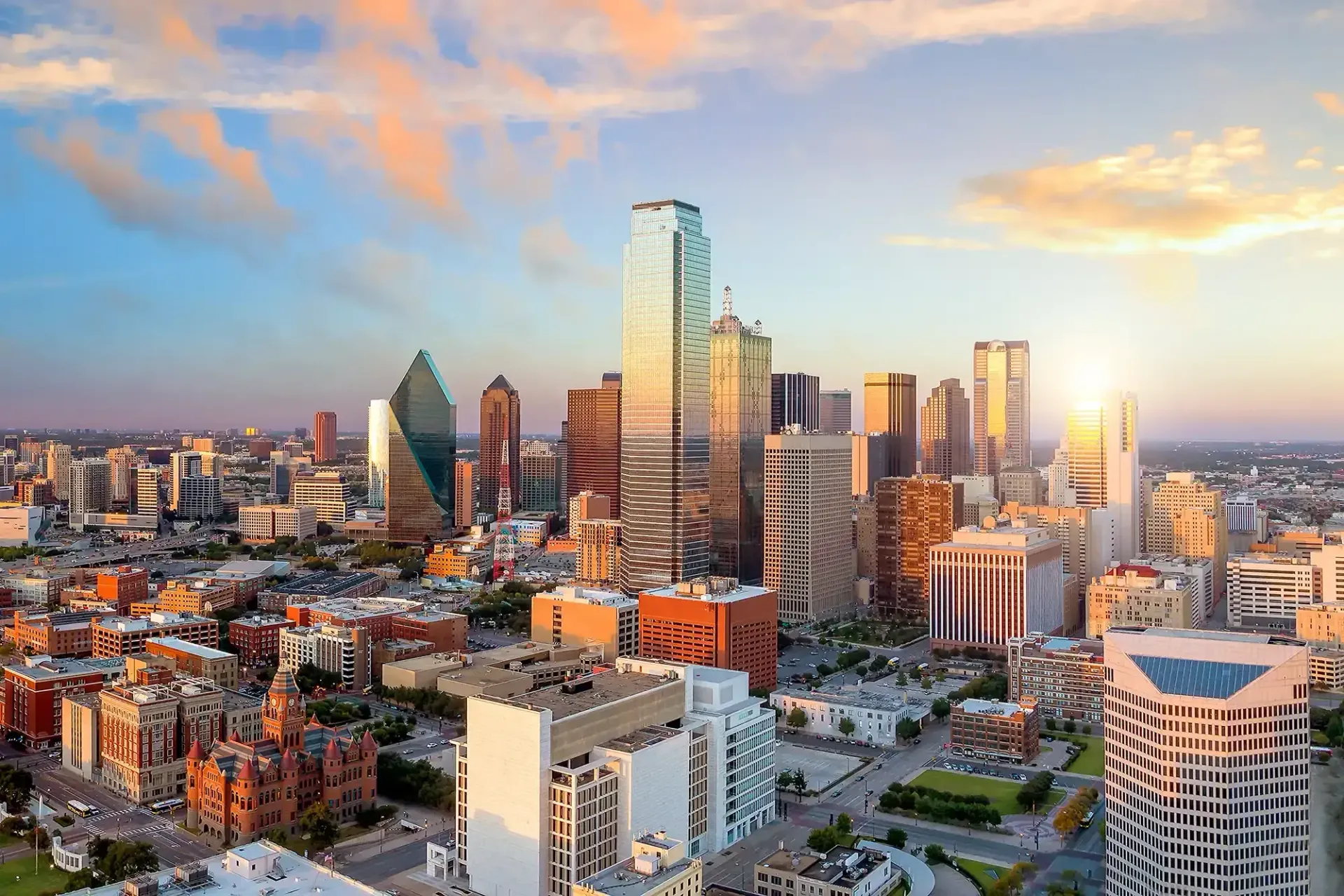 Downtown skyline with tall glass skyscrapers at sunset under a colorful sky