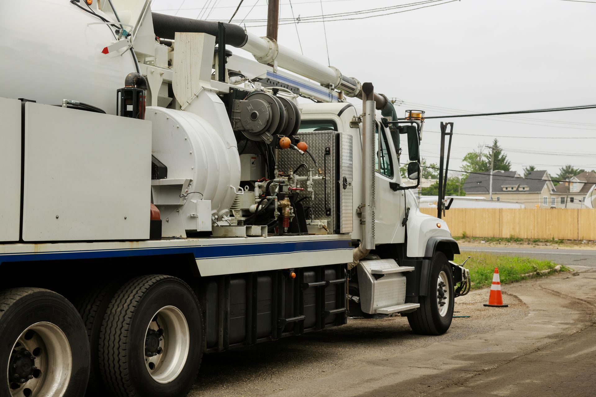White utility truck parked on a roadside with equipment on top and an orange traffic cone nearby