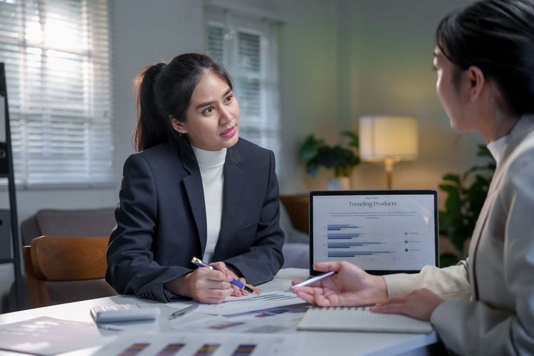 Two people discussing documents at a desk in a bright office