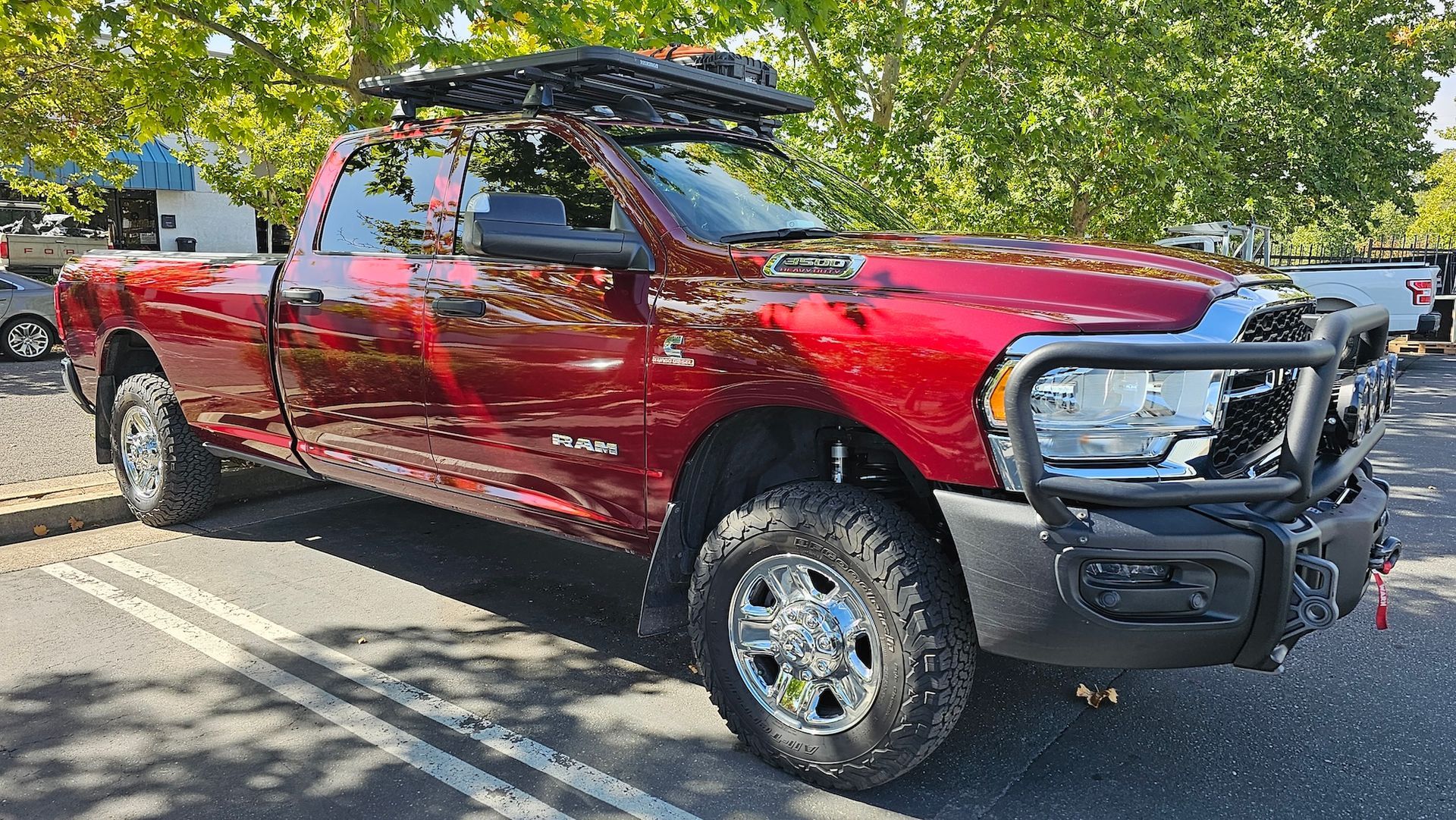 A red ram truck with a roof rack is parked in a parking lot.