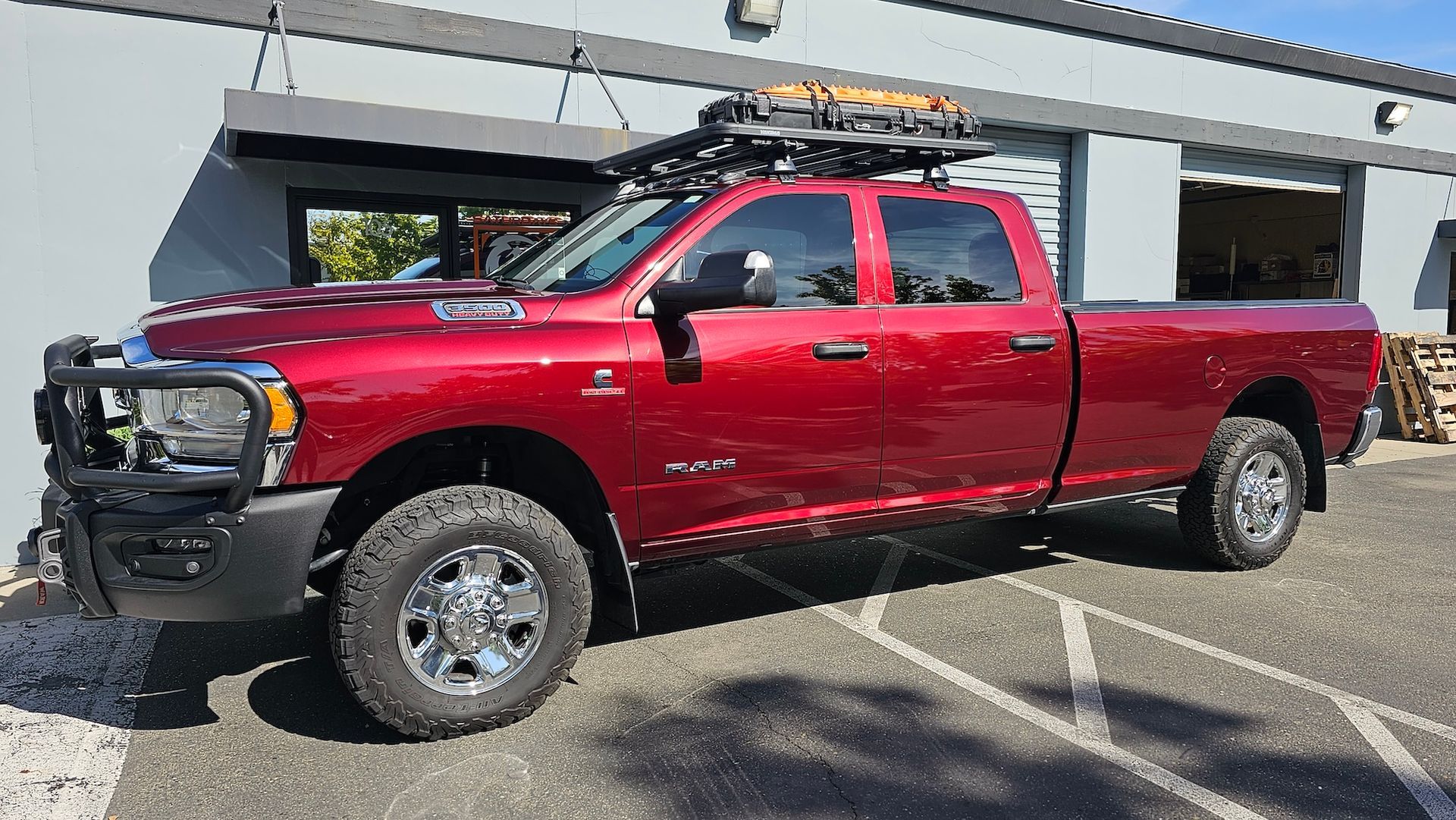 A red truck with a roof rack is parked in front of a building.