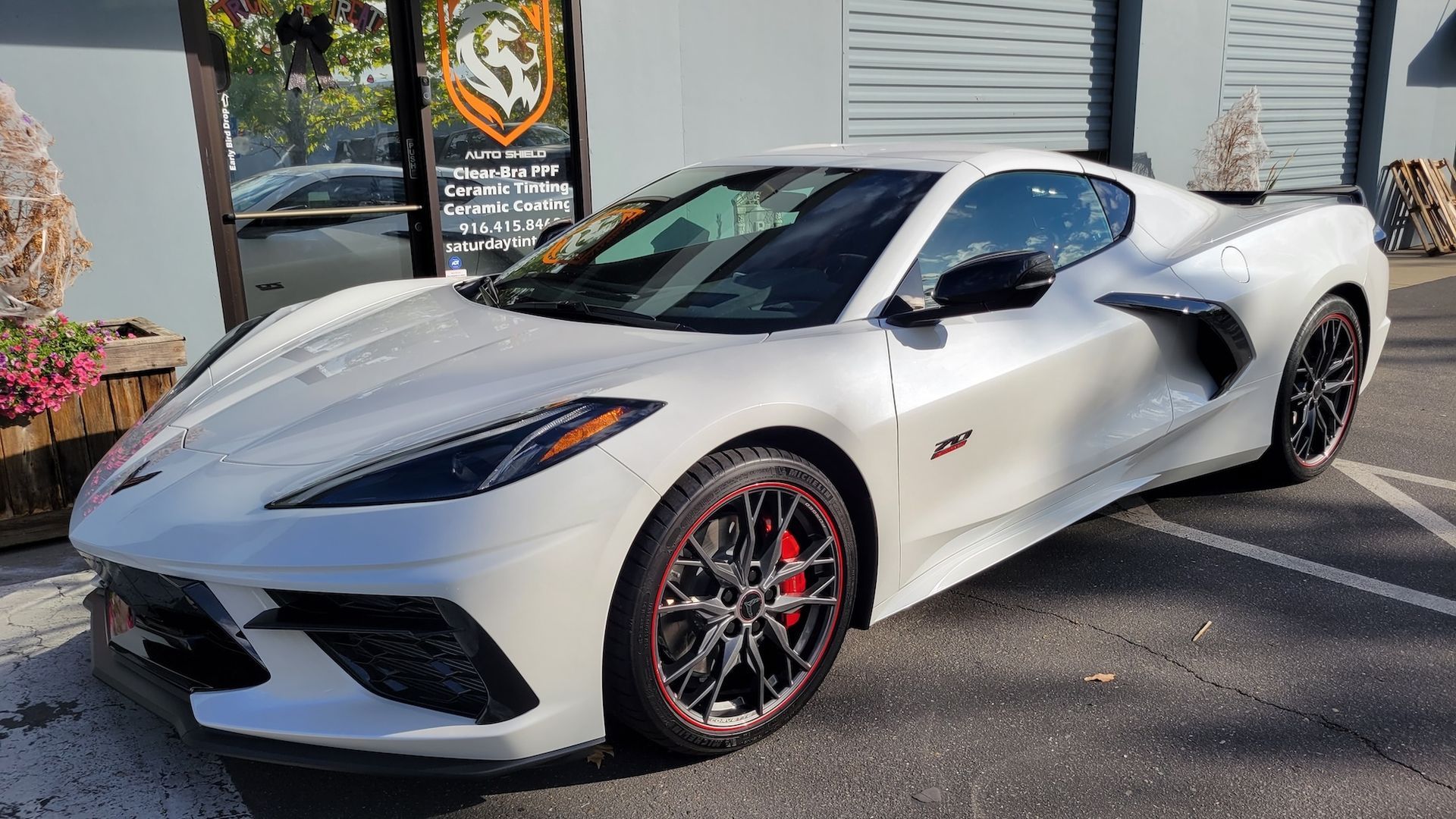 A white sports car is parked in a parking lot in front of a building.