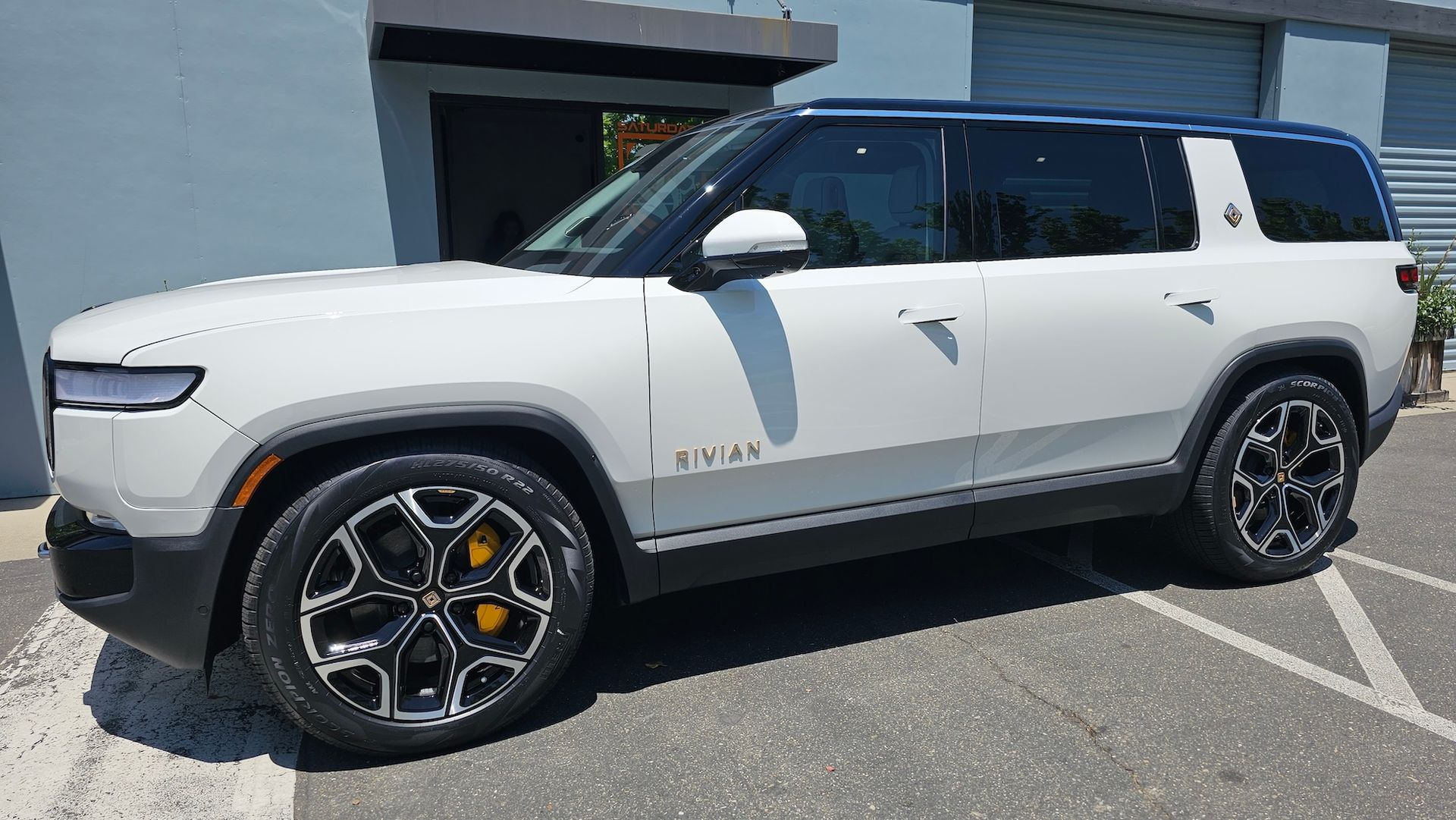 A white suv is parked in a parking lot in front of a building.