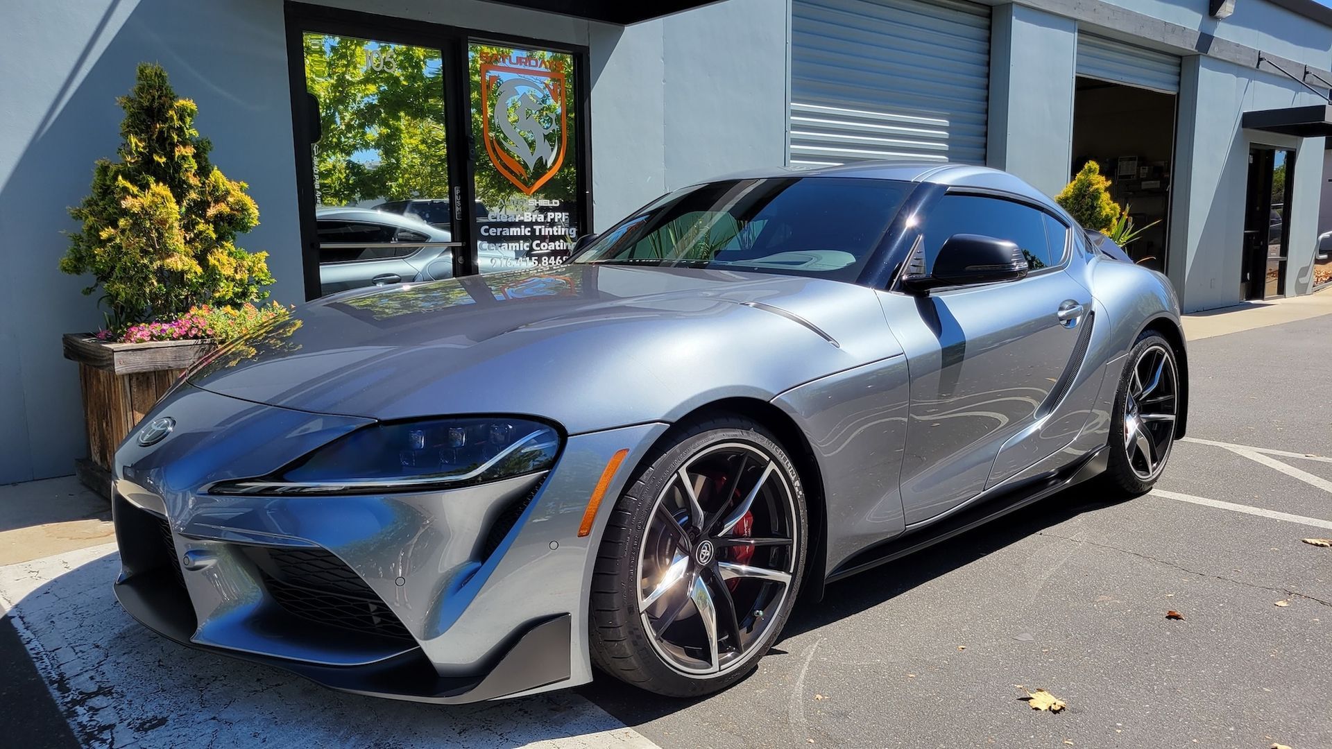 A gray sports car is parked in front of a building.
