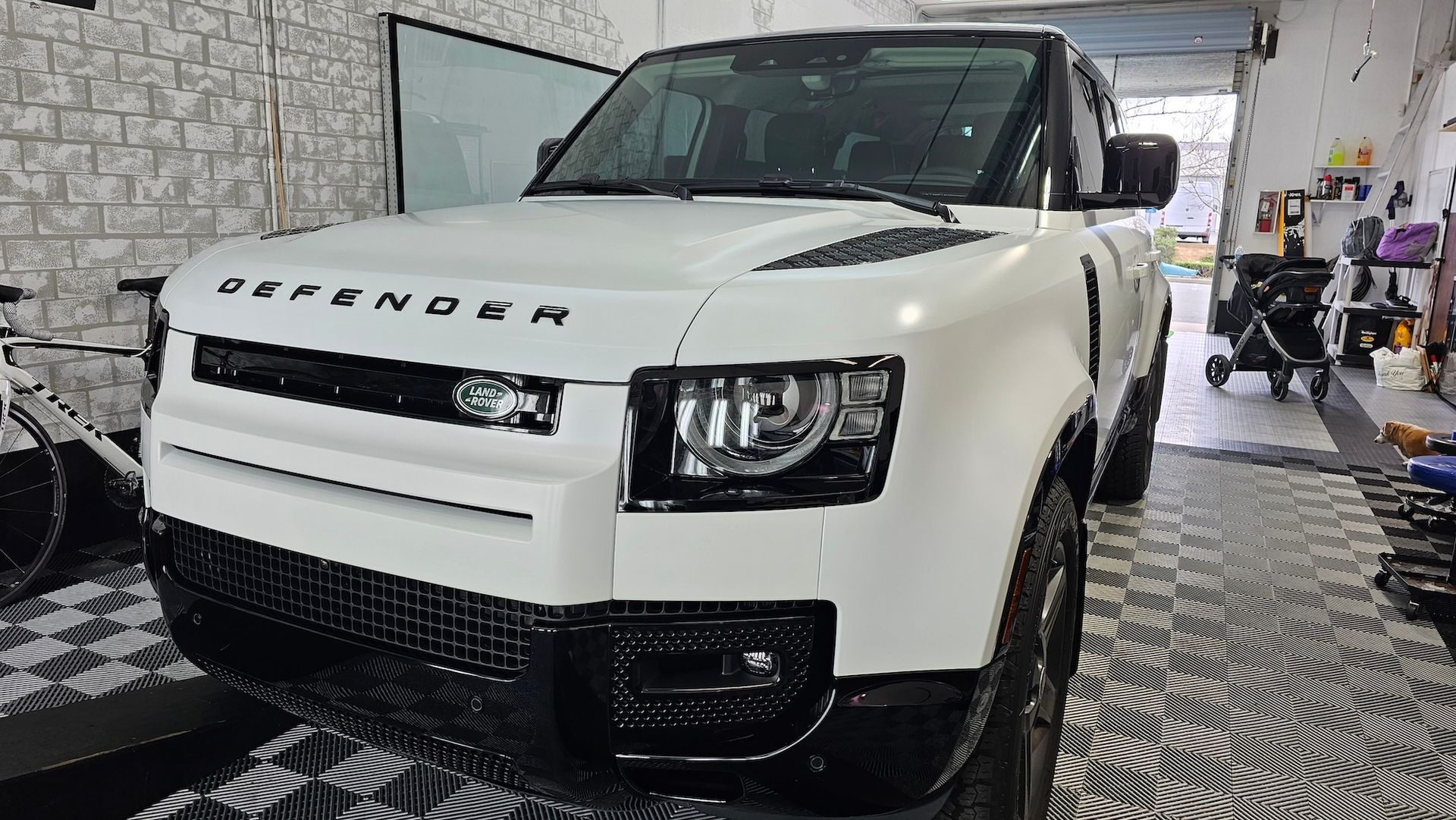 A white land rover defender is parked in a garage.