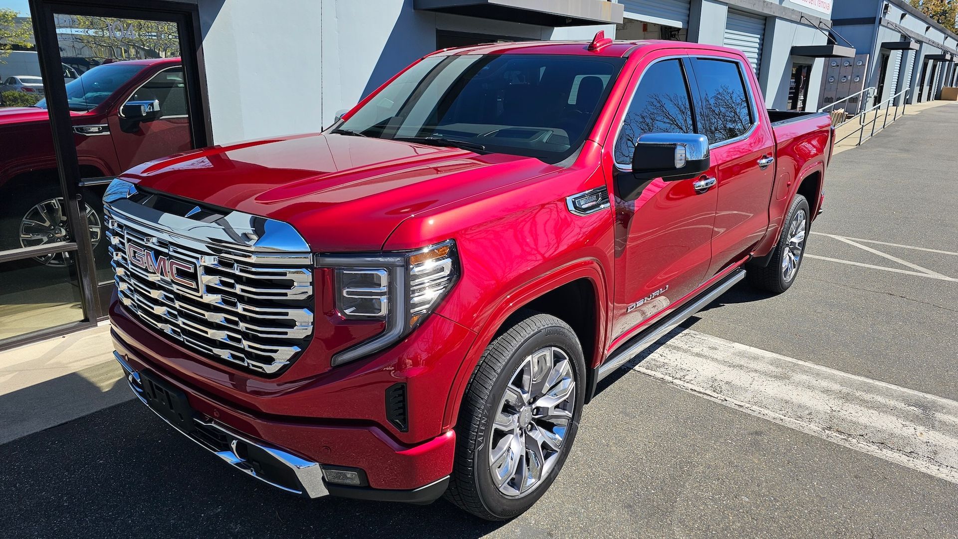 A red gmc sierra pickup truck is parked in a parking lot.