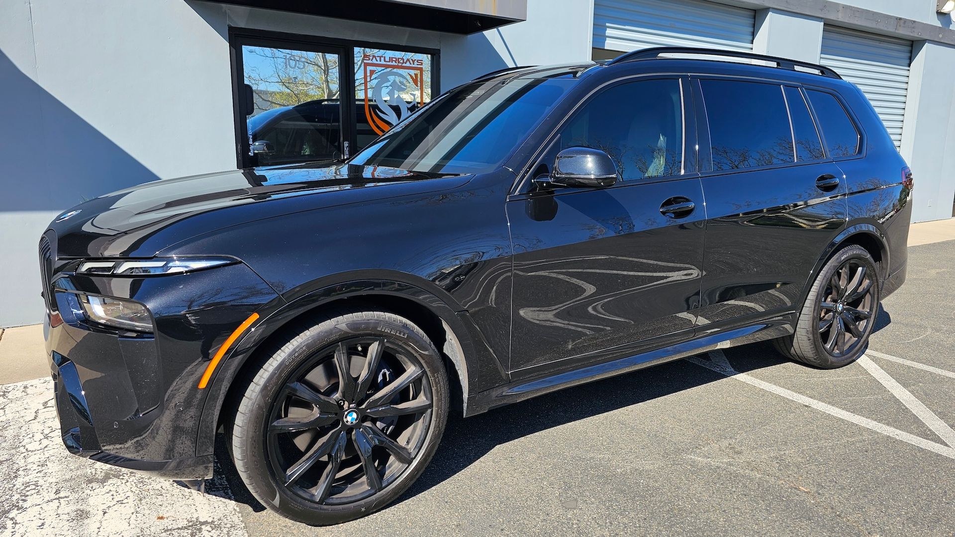 A black bmw x7 is parked in front of a building.