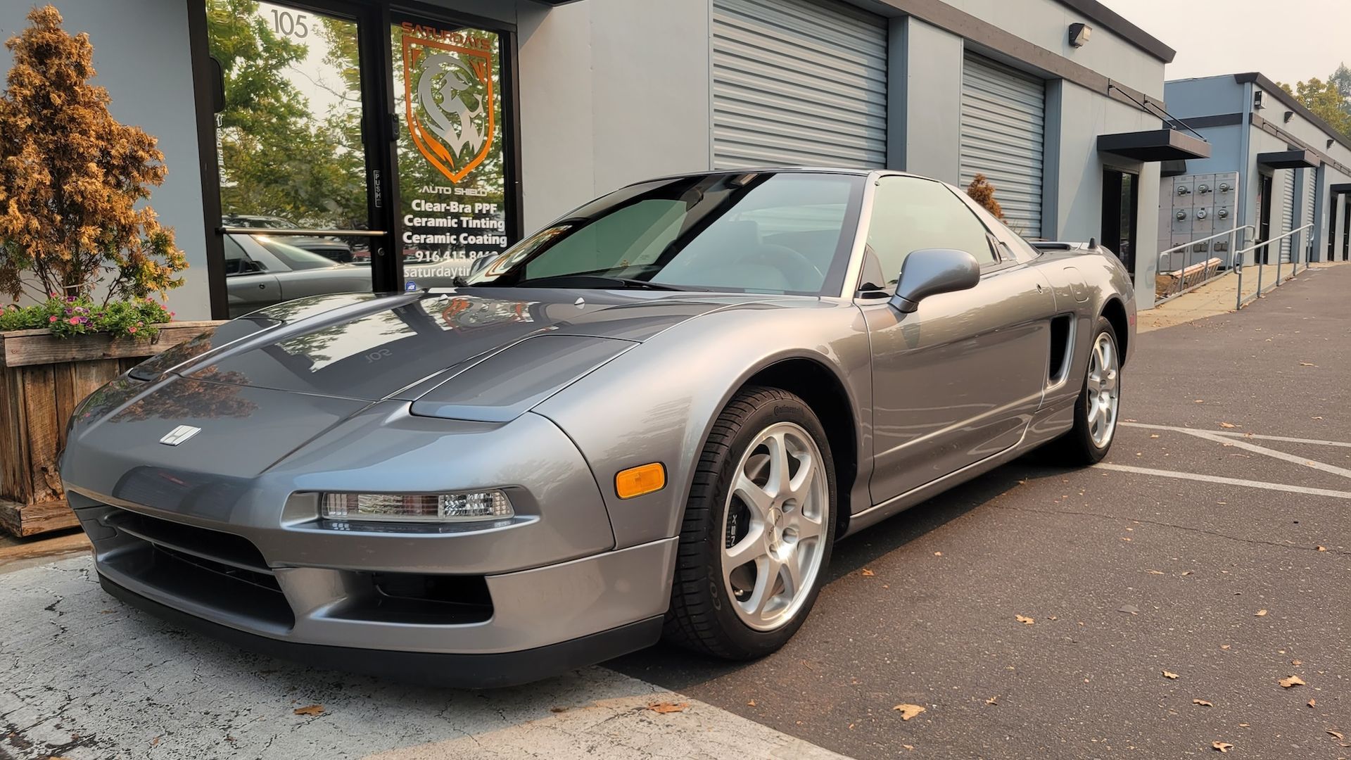A silver sports car is parked in front of a building.