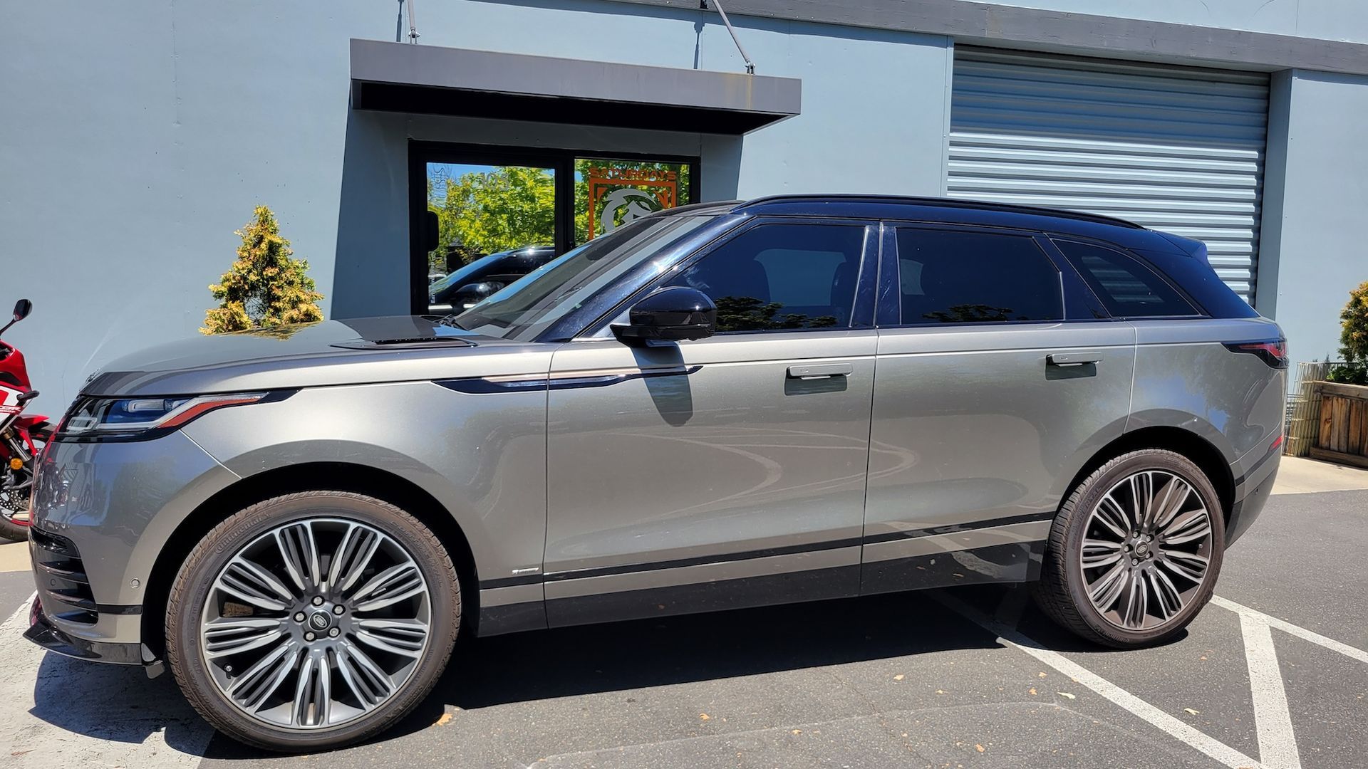 A silver range rover velar is parked in a parking lot in front of a building.