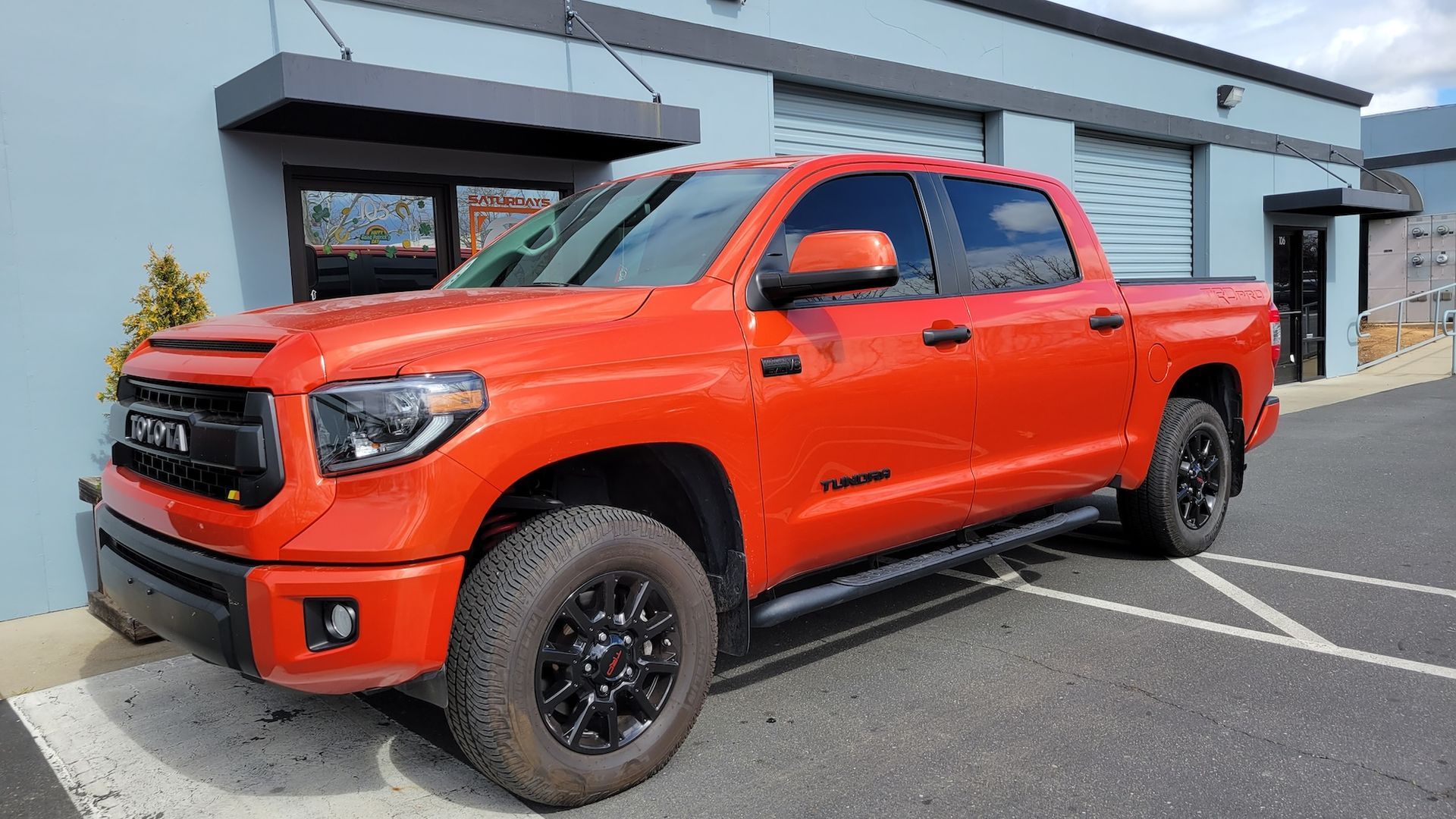 A red toyota tundra is parked in a parking lot in front of a building.