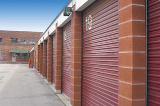 Red storage unit doors with brick columns, concrete path.