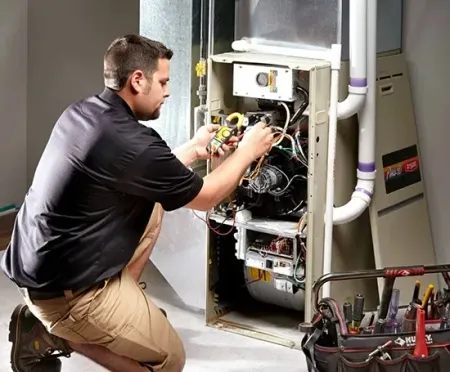 Technician repairing an open HVAC unit with tools in a utility room