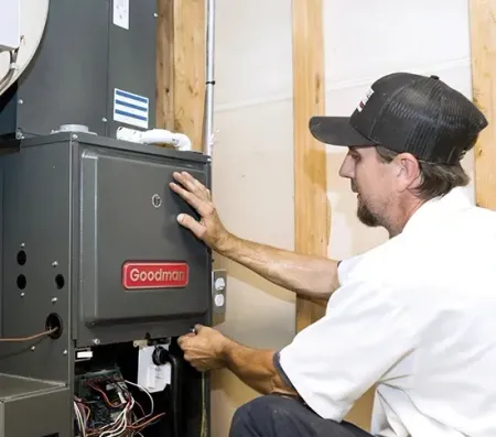 Technician inspecting a Goodman furnace unit in a utility room