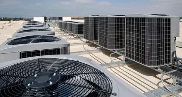 Rooftop HVAC units and large cooling fans on a sunlit industrial building