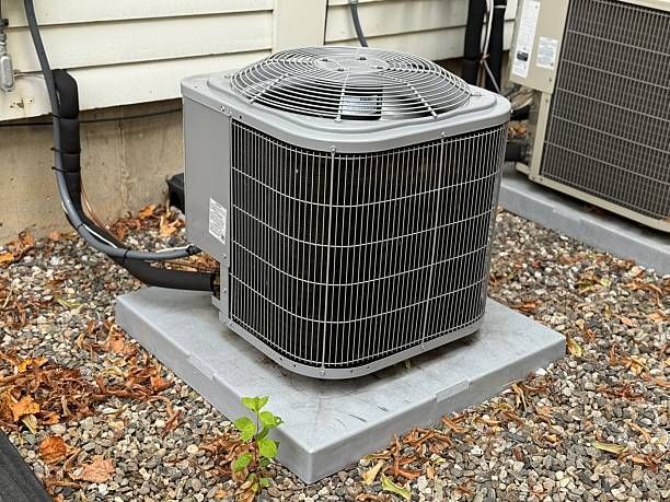 Outdoor air conditioner unit on a concrete pad beside a house