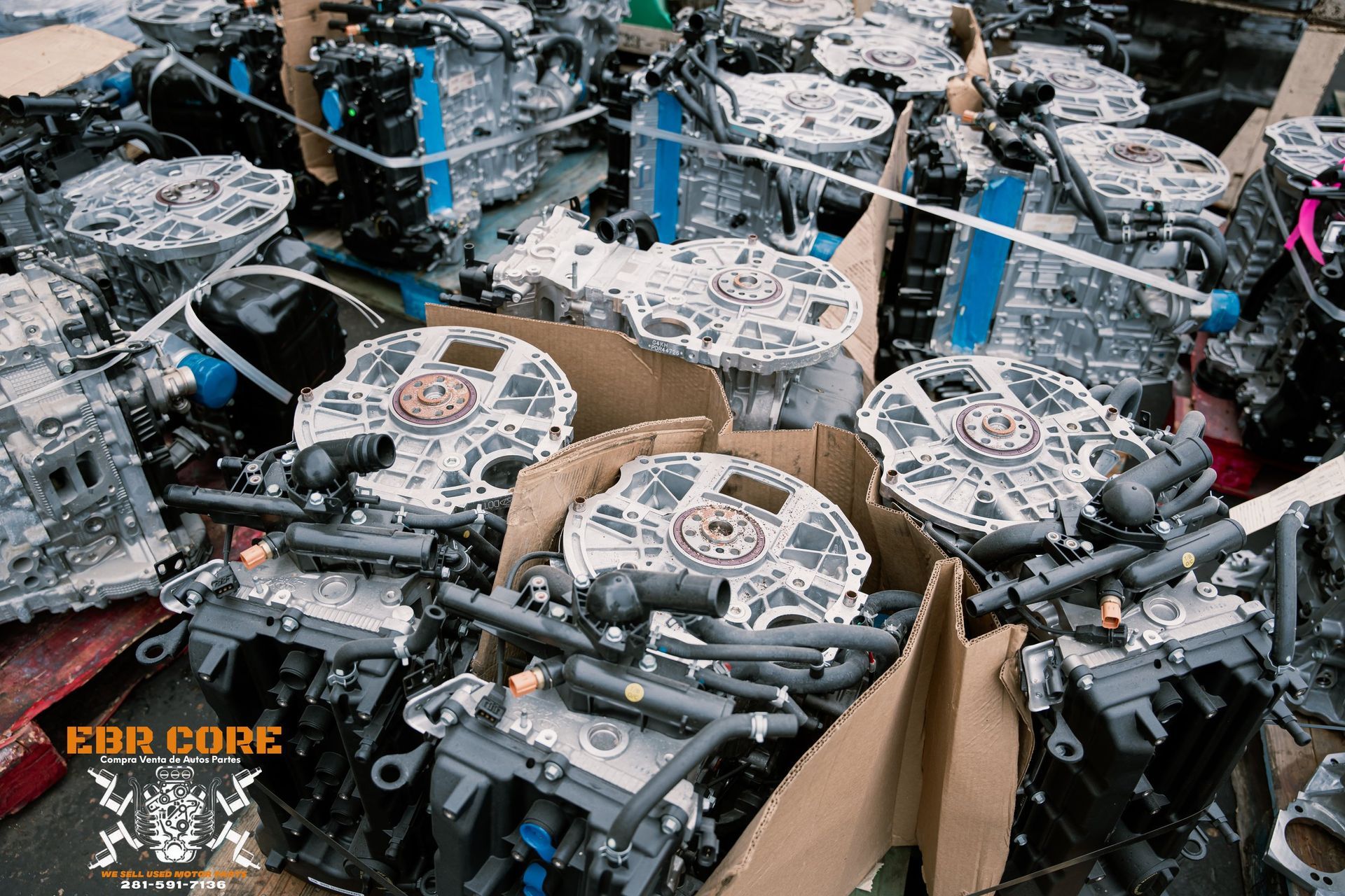 Engines piled in a disorganized heap, likely in a salvage yard. Cardboard boxes visible.