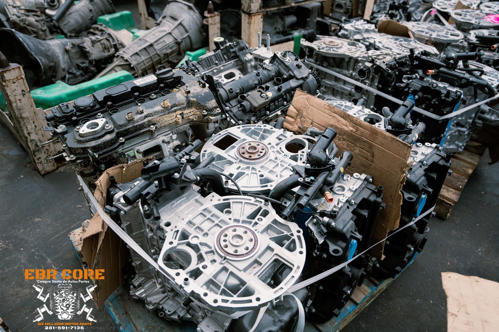Scrap automotive engines and transmissions piled up in a warehouse.