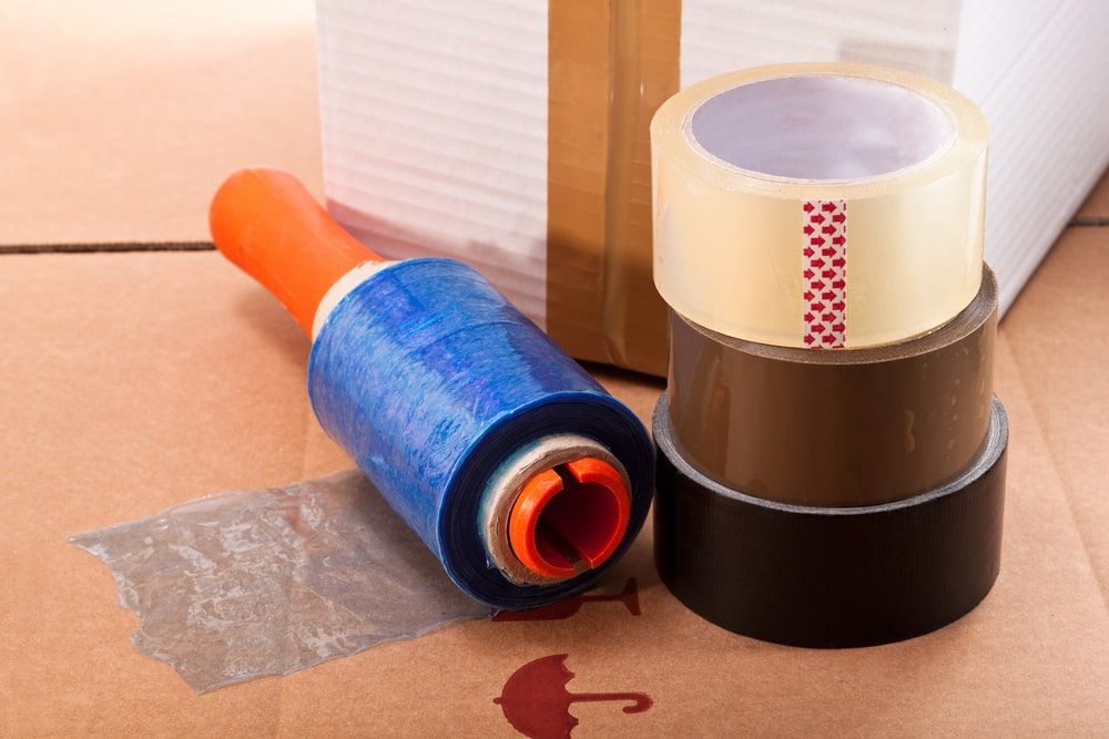 A Roll Of Packing Tape Is Sitting On Top Of A Cardboard Box — Greater Newcastle Removals In Swansea, NSW