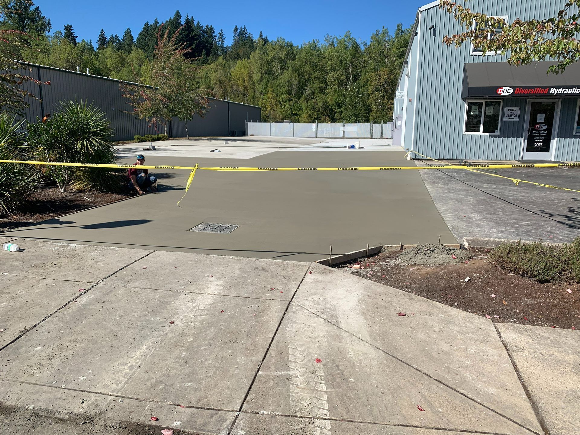 Empty parking lot with concrete ramp, yellow caution tape, and a building entrance on the right