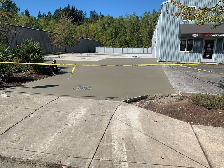 Empty parking lot with concrete ramp, yellow caution tape, and a building entrance on the right