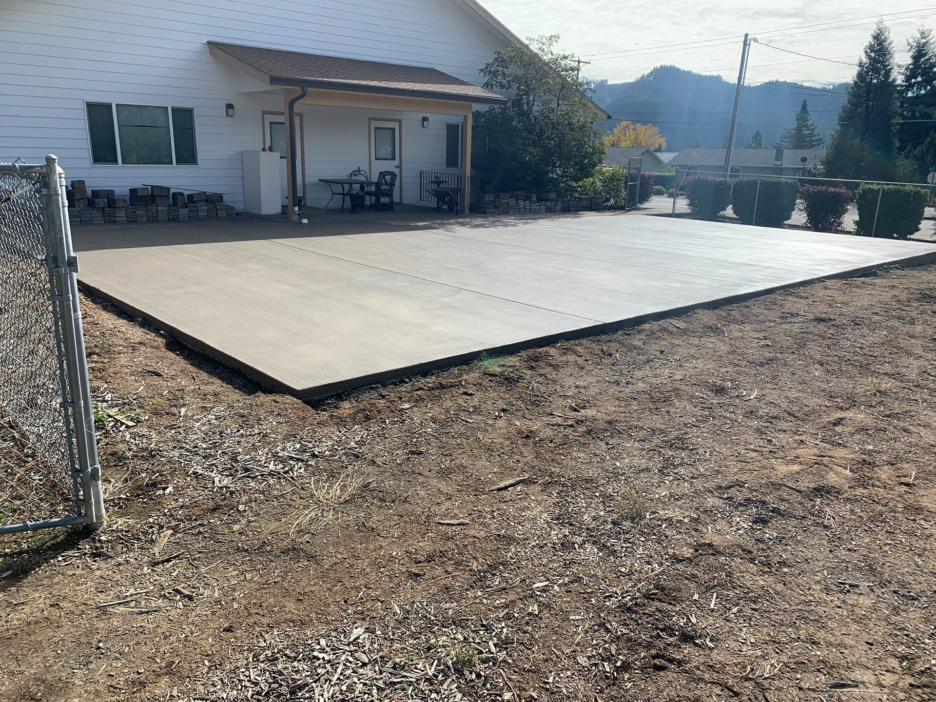 Concrete patio beside a house with gravel yard and mountains in the background