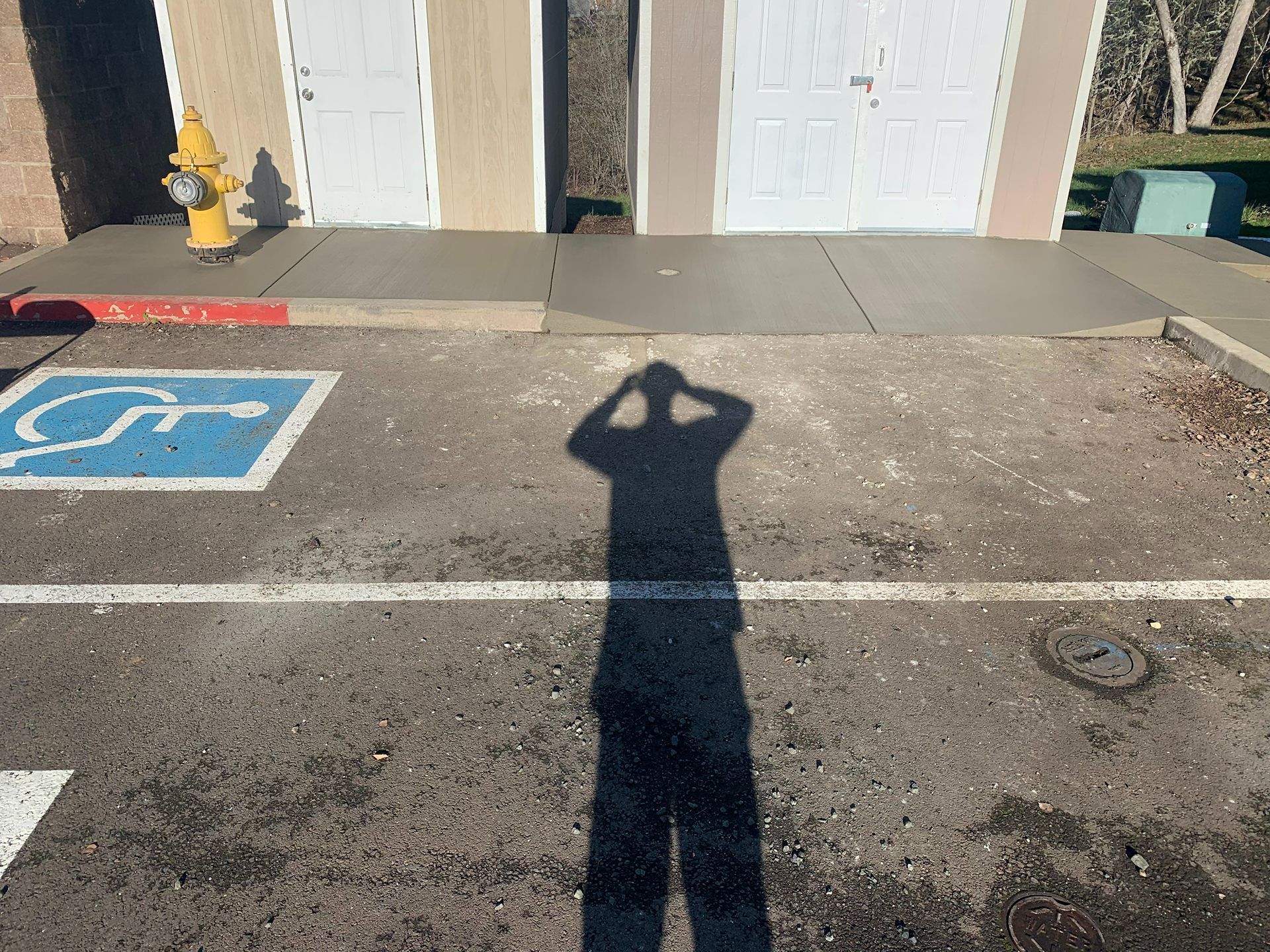 Accessible parking space in front of a building, with a person’s shadow in the foreground.