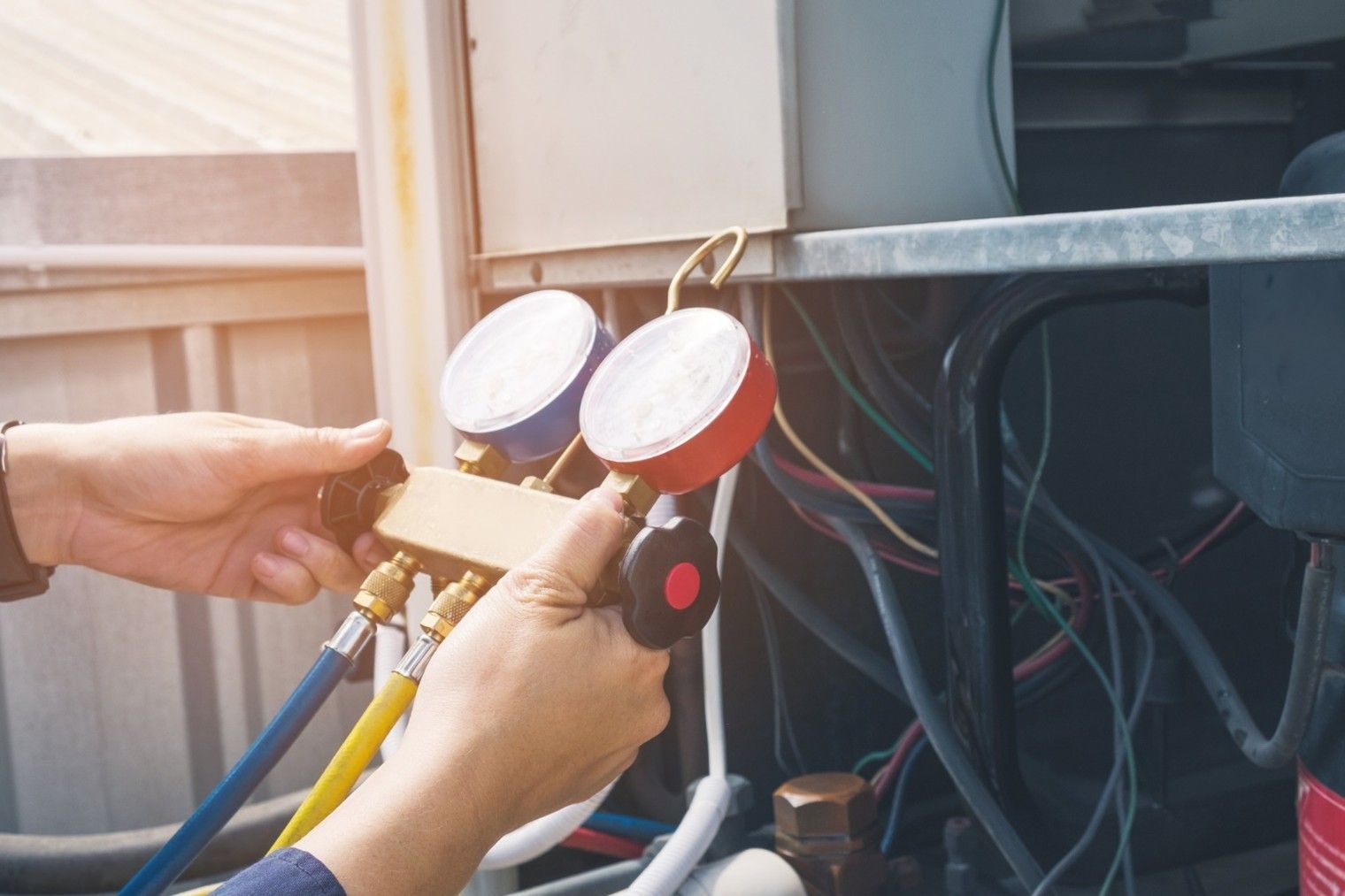 Person connecting gauges to an air conditioning unit.