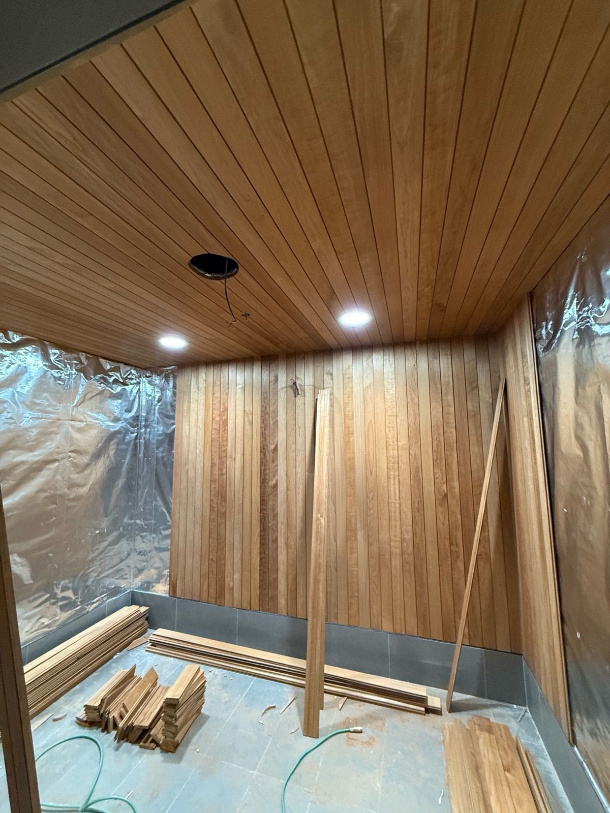 Wood-paneled sauna interior with bench, central post, and warm ceiling lights