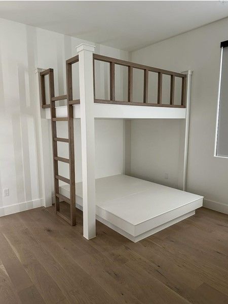 White and brown bunk bed in a room with wood flooring.
