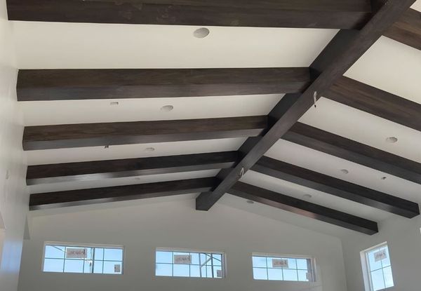 Dark wooden beams on a white vaulted ceiling. Windows are below.
