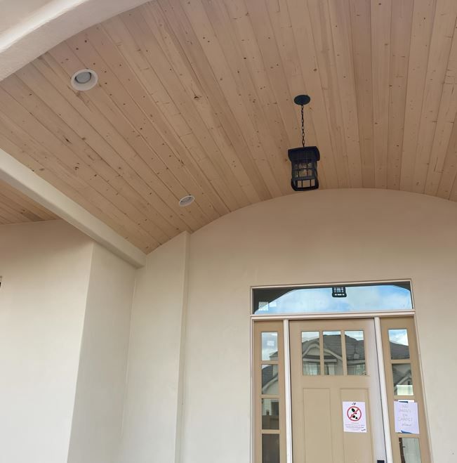 Covered entrance with arched wood ceiling, hanging lantern, and glass double doors.