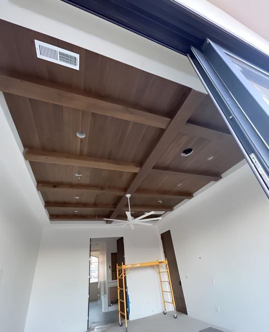 Partially finished room with a wood-paneled ceiling and a yellow scaffold near a doorway