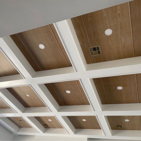 Wood paneled ceiling with white beams, recessed lighting, and a vent.