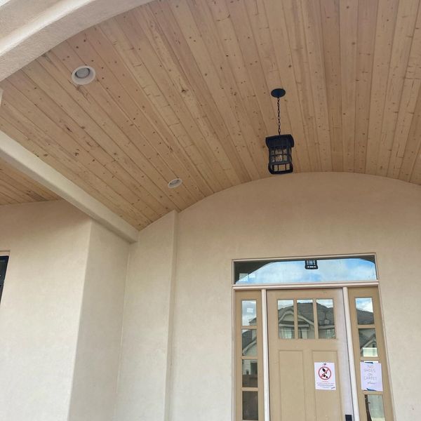 Beige entryway with wooden ceiling, recessed lights, and a hanging lantern above a door.