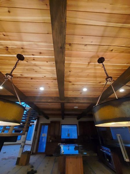 Wooden ceiling with beams, pendant lights, and kitchen interior visible below.