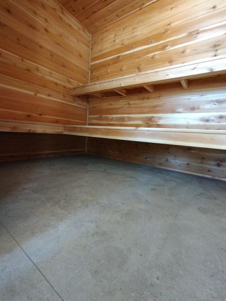 Wooden sauna interior with two benches and a concrete floor.