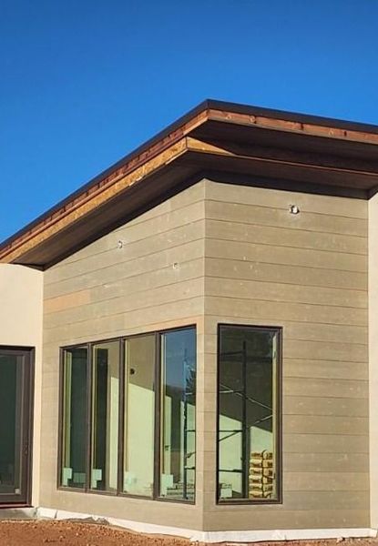 Beige modern building exterior with large windows under clear blue sky.