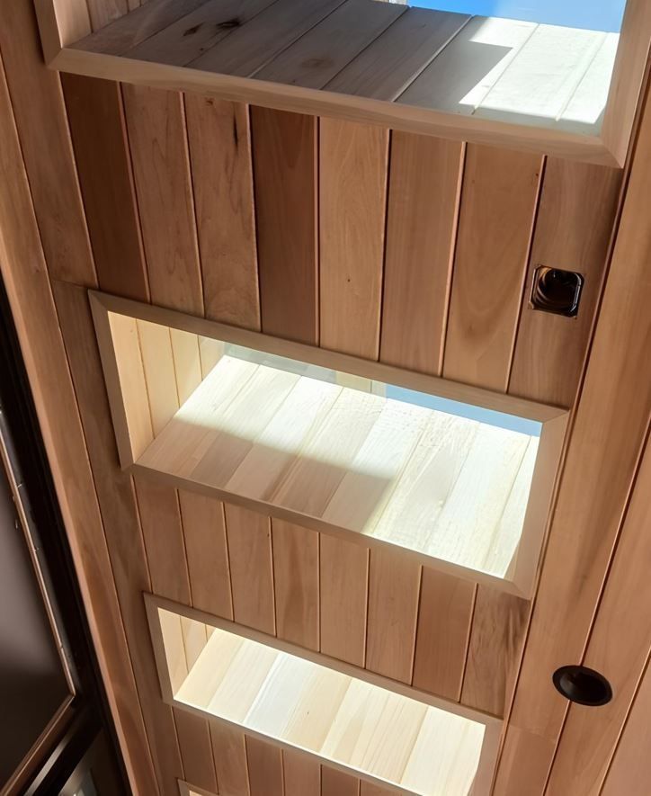 Wooden cabinet with three illuminated shelves and black handles, viewed close up.