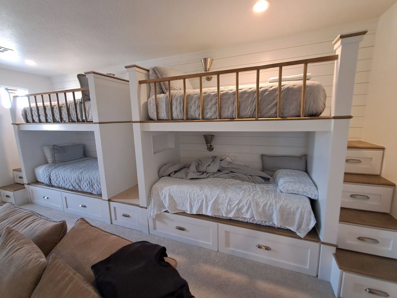 White bunk beds with storage drawers, wooden accents, and a staircase.