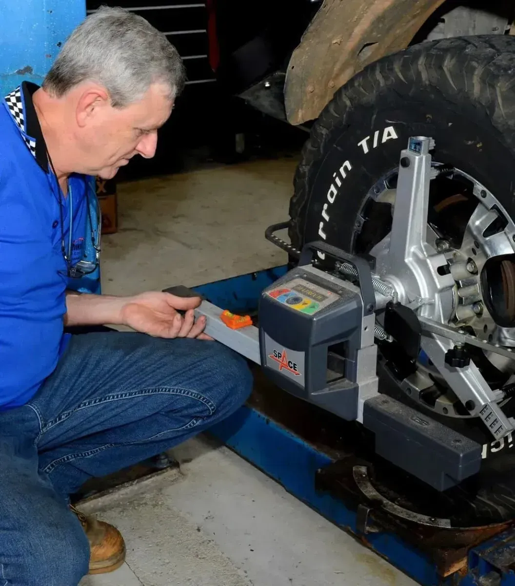 Mechanic Using Wheel Alignment Machine on a Car Tire in a Garage — Advanced Auto Electrics & Mechanical in Innisfail, QLD