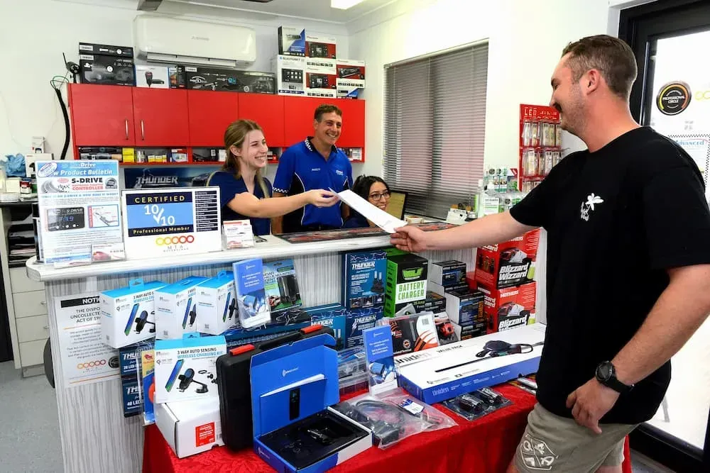 a Customer Smiles, Receiving a Receipt From a Clerk Behind a Counter — Advanced Auto Electrics & Mechanical in Innisfail, QLD