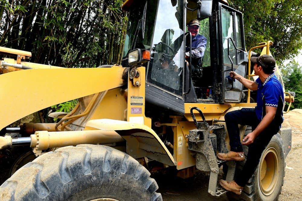 a Man Climbing Onto a Yellow Construction Vehicle — Advanced Auto Electrics & Mechanical in Innisfail, QLD