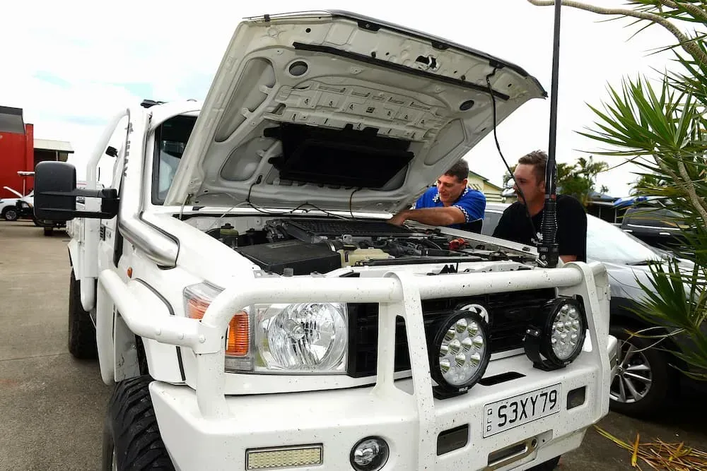 Two Men Working on the Engine of a White Truck With the Hood Open — Advanced Auto Electrics & Mechanical in Innisfail, QLD