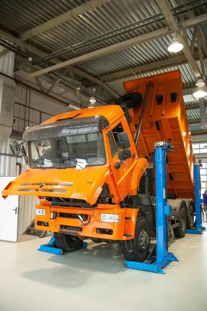 Orange Dump Truck on a Lift in a Repair Shop — Advanced Auto Electrics & Mechanical in Innisfail, QLD